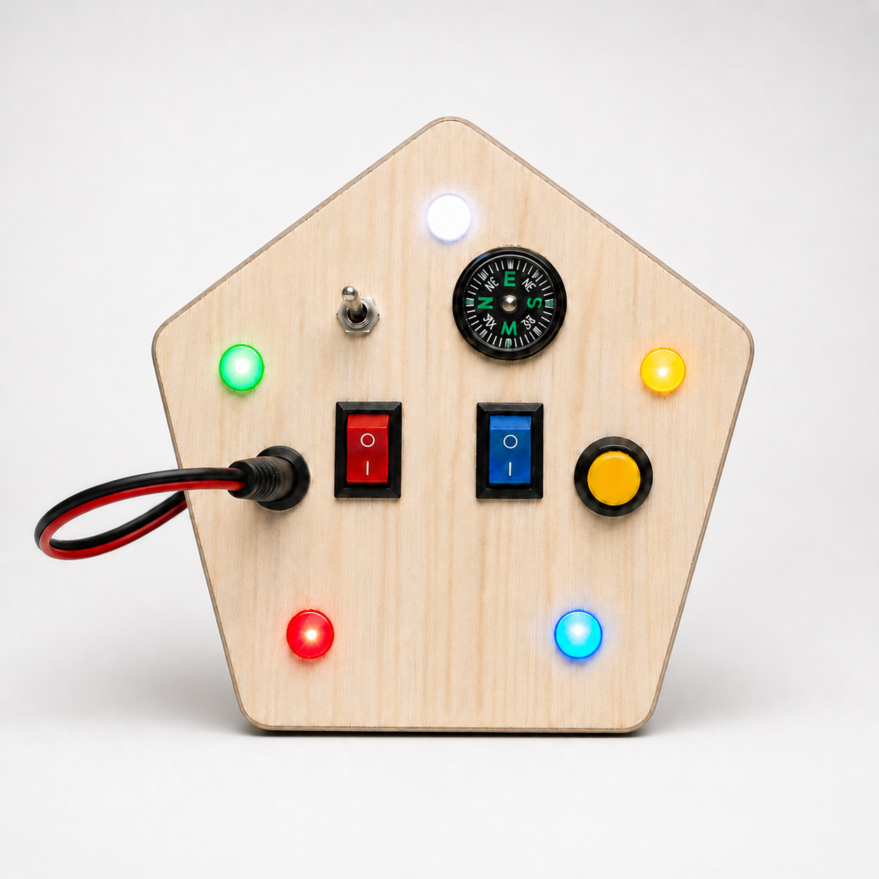 Front view of RedMonkys Pentagon Explorer wooden busy board with five tactile switches, soft LED lights, plug connector, and compass
